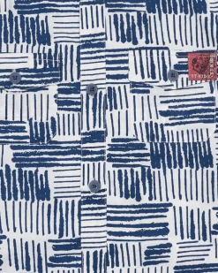 Chemise blanche pour garçon avec imprimé géométrique bleu et poche décorative.