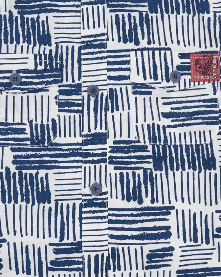 Chemise blanche pour garçon avec imprimé géométrique bleu et poche décorative.