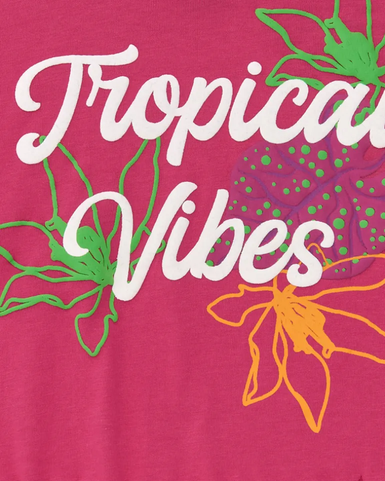 T-shirt pour fille en fuchsia avec imprimé tropical et franges sur le bas.